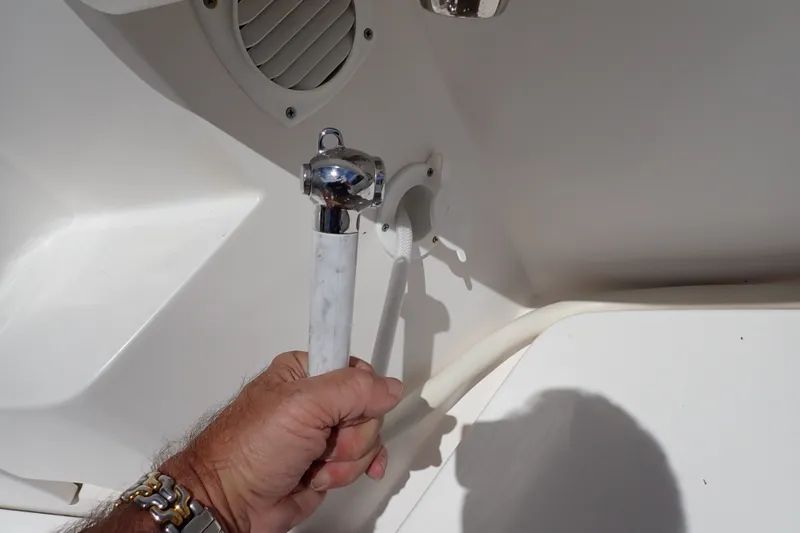 Slide: The Image of Hand holding a shower handle on a 2005 Bertram 390 boat deck. - 107