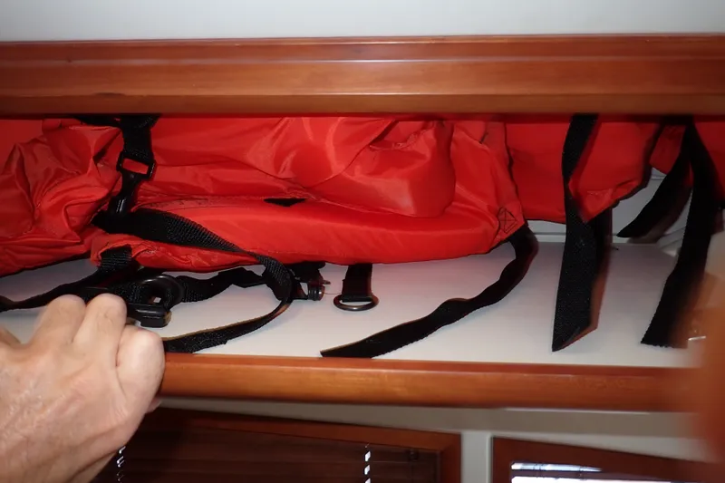 Slide: The Image of Red life jackets stored in a wooden compartment on a 2005 Bertram 390 boat. - 78