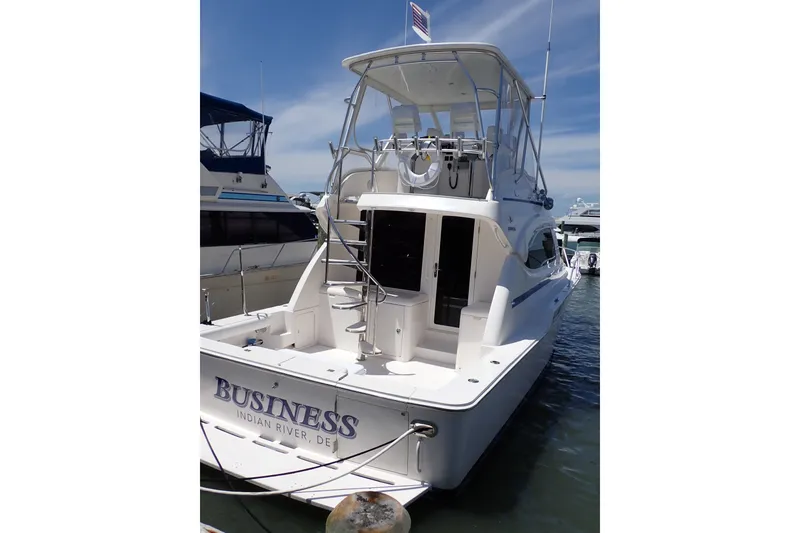 Slide: The Image of 2005 Bertram 390 yacht docked, rear view with flybridge and ladder, named "Business." - 4