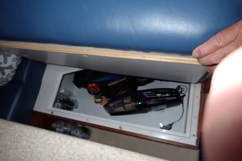 Slide: The Image of Storage compartment in a 2005 Bertram 390 boat, containing various items and a handheld vacuum. - 71
