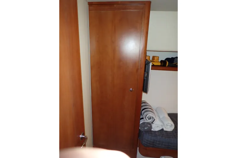 Slide: The Image of Interior of 2005 Bertram 390 yacht with wooden cabinet and cozy bedding. - 94