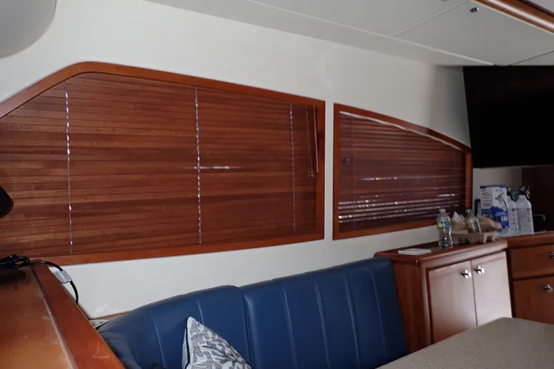 Slide: The Image of Interior of a 2005 Bertram 390 yacht with wooden blinds and blue seating. - 101
