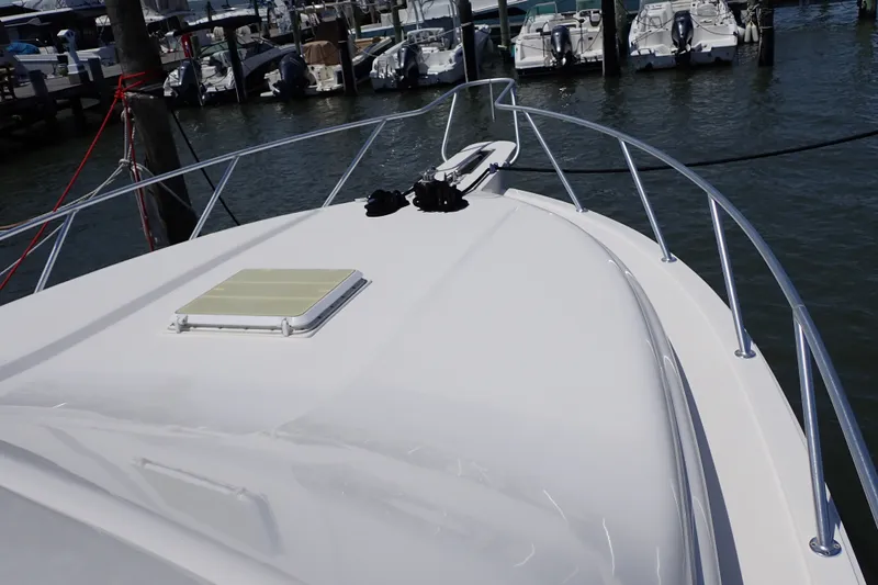 Slide: The Image of 2005 Bertram 390 yacht bow view at marina, showcasing sleek design and railing. - 28