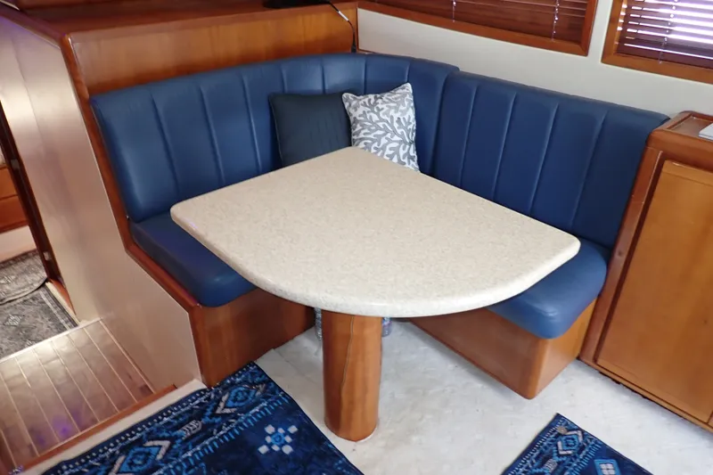 Slide: The Image of 2005 Bertram 390 yacht interior with blue cushioned seating and a beige table. - 70