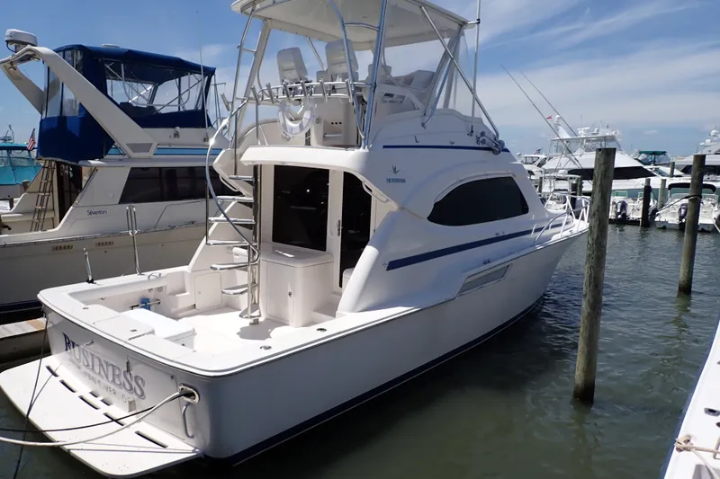 Slide: The Image of 2005 Bertram 390 yacht docked at marina, featuring sleek design and spacious deck. - 2