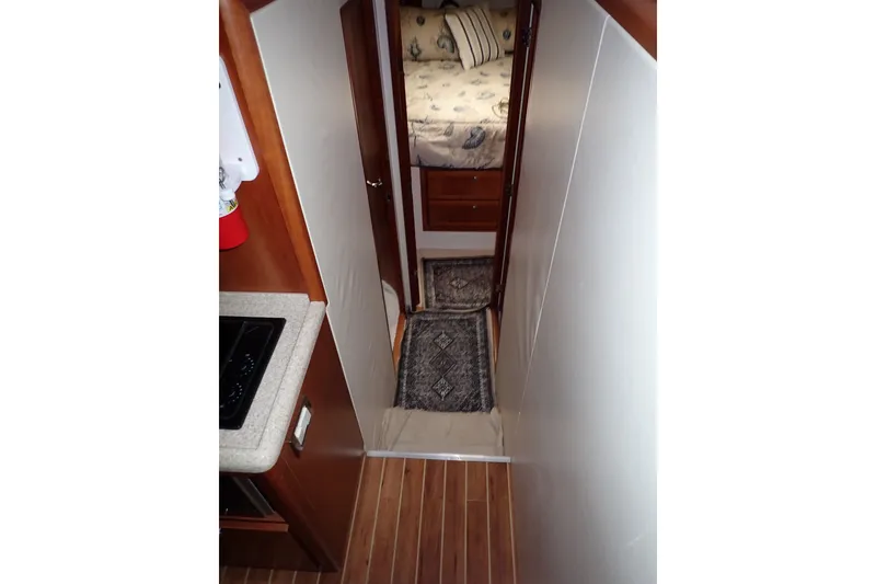 Slide: The Image of Interior view of 2005 Bertram 390 yacht, featuring hallway and cozy bedroom. - 50