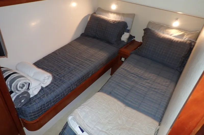 Slide: The Image of Twin beds in a 2005 Bertram 390 cabin with blue bedding and soft lighting. - 92