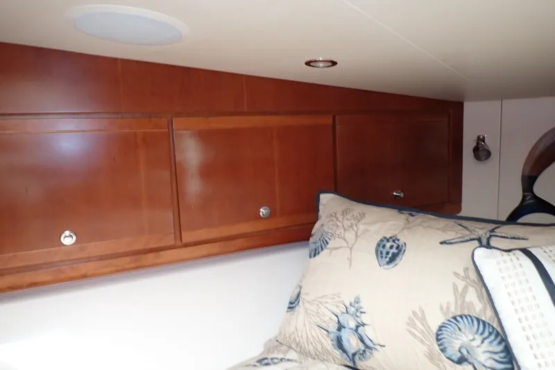 Slide: The Image of Wooden cabinets and nautical-themed pillows in a 2005 Bertram 390 interior. - 83