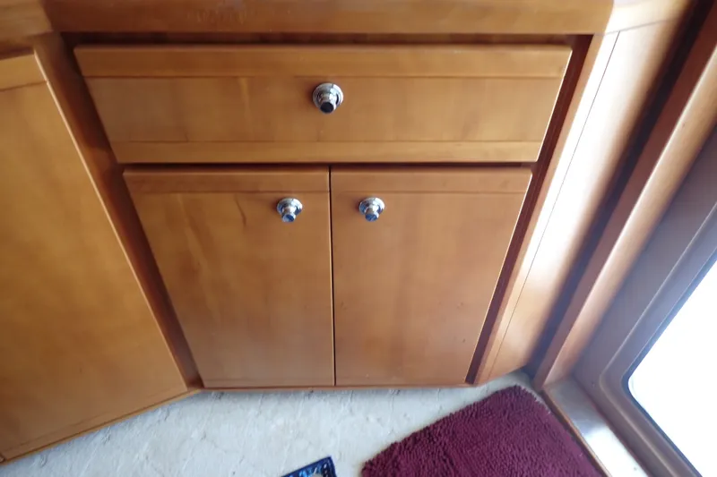 Slide: The Image of Wooden cabinet with chrome knobs inside a 2005 Bertram 390 boat interior. - 74