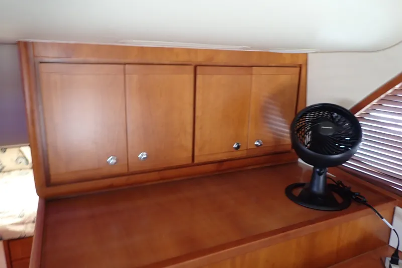 Slide: The Image of Wooden cabinet interior of 2005 Bertram 390 yacht with a small black fan. - 60