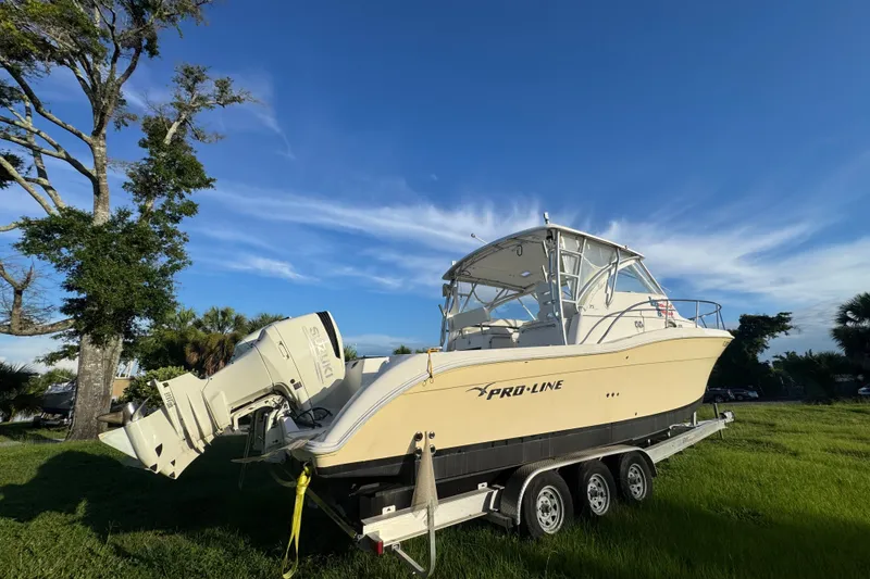 Slide: The Image of 2006 Pro-Line 35 Express boat on trailer, parked on grassy area under clear blue sky. - 24