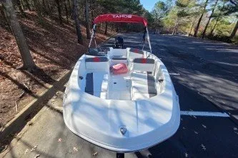 Slide: The Image of 2026 Tahoe T16 boat with red canopy parked in wooded area. - 67