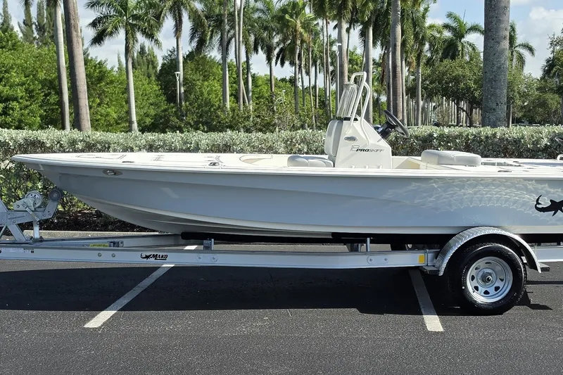 The Image of 2026 Mako 18 Pro Skiff boat on trailer, parked with palm trees in background. - 0