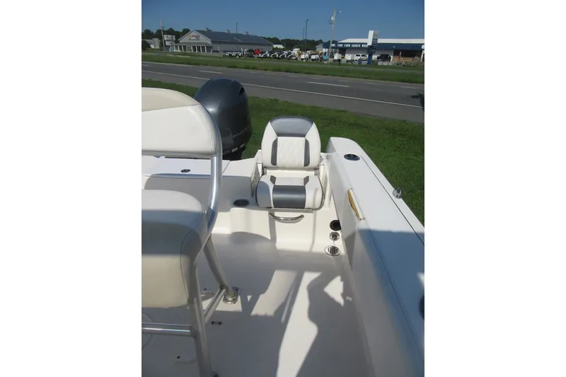 Slide: The Image of 2015 Robalo R180 Center Console boat interior with seating and motor, parked near a road. - 19
