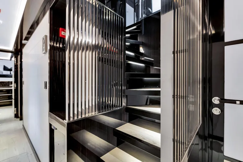 Slide: The Image of Modern interior staircase on a 2021 Sirena 88 yacht, featuring sleek black and metallic design. - 95