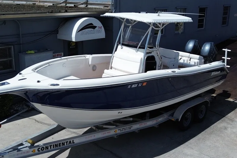 The Image of 2005 Triton 2690 CC on a trailer, featuring a blue hull and twin outboard engines. - 0