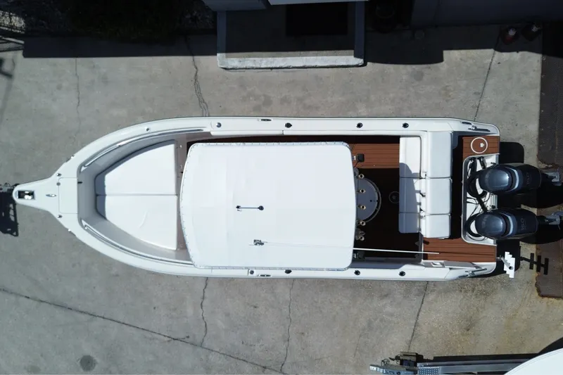Slide: The Image of Aerial view of a white 2005 Triton 2690 CC boat with twin outboard engines, on a concrete surface. - 15