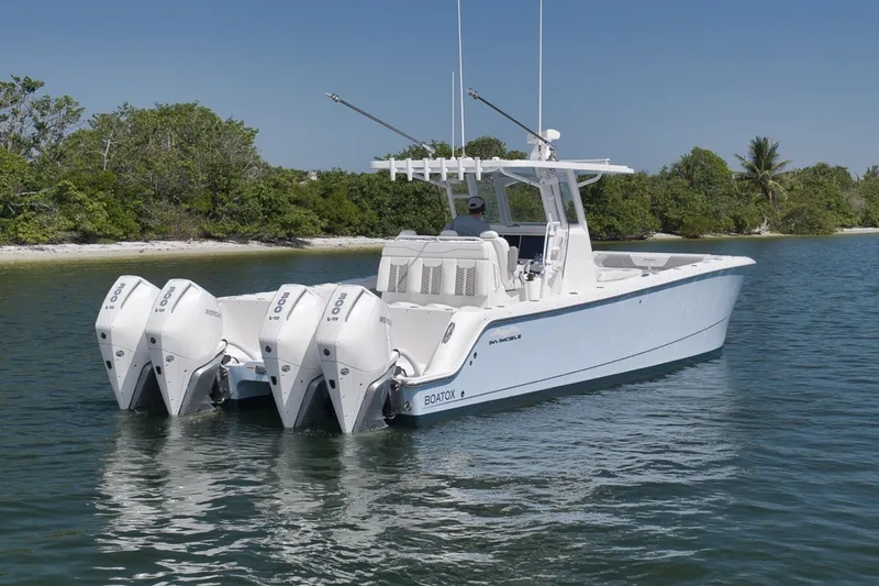 Slide: The Image of 2025 Invincible 35 Catamaran with quad engines cruising near a lush shoreline. - 12