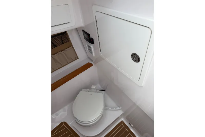 Slide: The Image of 2024 Southport 33 DC boat interior with compact marine toilet and storage compartment. - 17