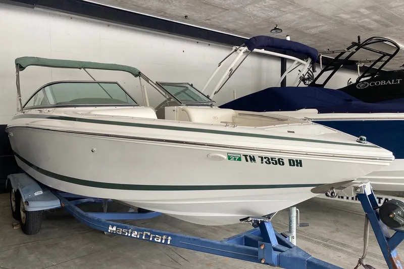 The Image of 2002 Cobalt 206 boat on trailer in indoor storage, featuring green accents. - 1