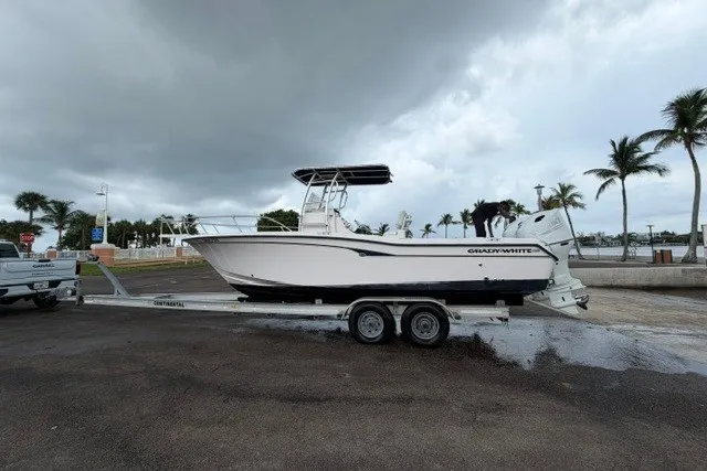Slide: The Image of 2003 Grady-White Advance 257 boat on trailer, parked near palm trees under cloudy sky. - 15