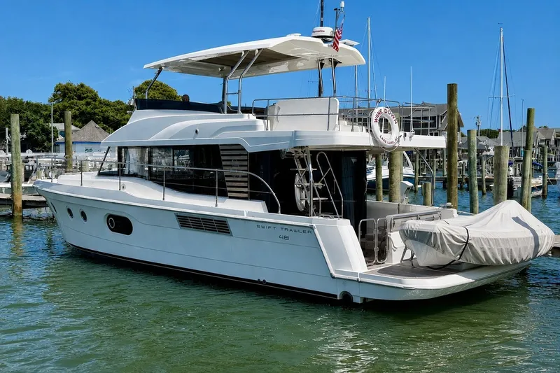 Slide: The Image of 2025 Beneteau Swift Trawler 48 docked at marina, showcasing sleek design and modern features. - 1