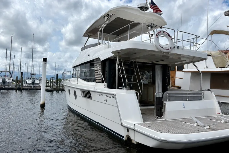 Slide: The Image of 2025 Beneteau Swift Trawler 48 docked at marina under cloudy sky. - 3