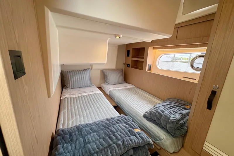 Slide: The Image of 2025 Beneteau Swift Trawler 48 cabin with twin beds and window view. - 8