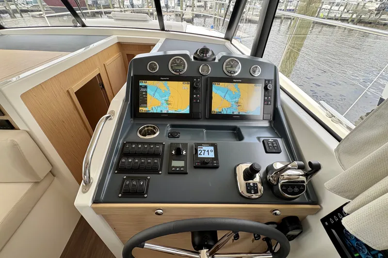 Slide: The Image of Helm of 2025 Beneteau Swift Trawler 48 with navigation screens and controls. - 12