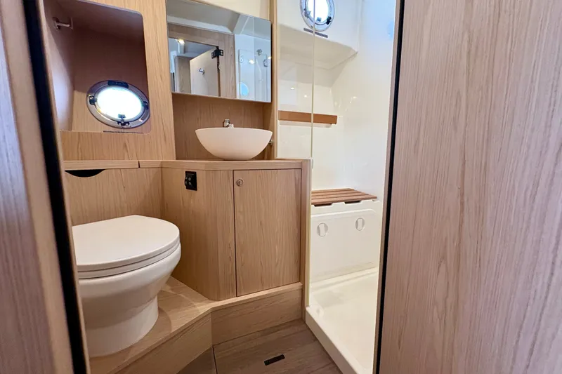Slide: The Image of Modern bathroom interior of 2025 Beneteau Swift Trawler 48 yacht, featuring wood accents and porthole. - 7