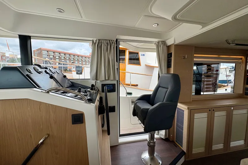 Slide: The Image of Interior of 2025 Beneteau Swift Trawler 48, featuring helm station and comfortable seating. - 13