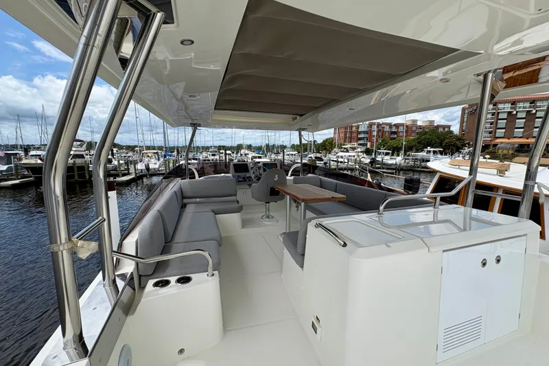 Slide: The Image of 2025 Beneteau Swift Trawler 48 interior with seating and helm, docked at marina. - 26