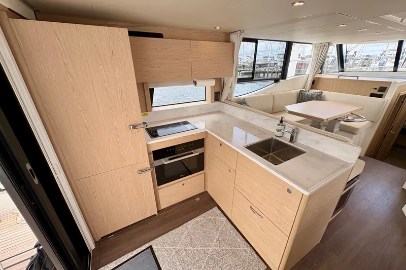 Slide: The Image of Modern kitchen interior of 2025 Beneteau Swift Trawler 48 with wood cabinetry and dining area. - 18
