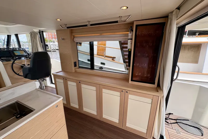Slide: The Image of Interior of 2025 Beneteau Swift Trawler 48, featuring helm, cabinetry, and window view. - 19