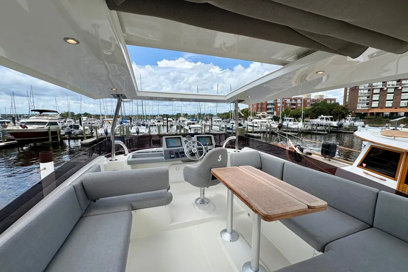 Slide: The Image of 2025 Beneteau Swift Trawler 48 interior with seating and helm, docked at marina. - 30