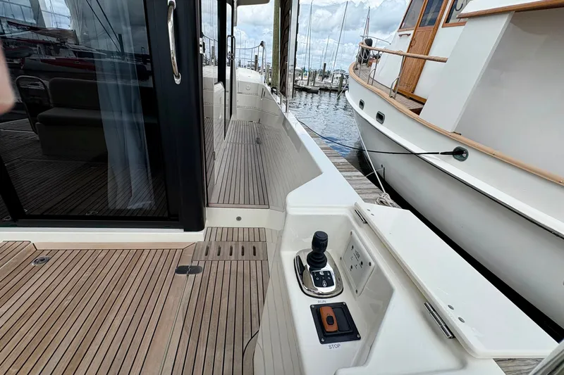 Slide: The Image of 2025 Beneteau Swift Trawler 48 docked, showcasing sleek deck design and control panel. - 24