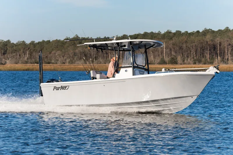 The Image of 2027 Parker 230 Coastal Elite boat cruising on a serene lake with forest backdrop. - 1