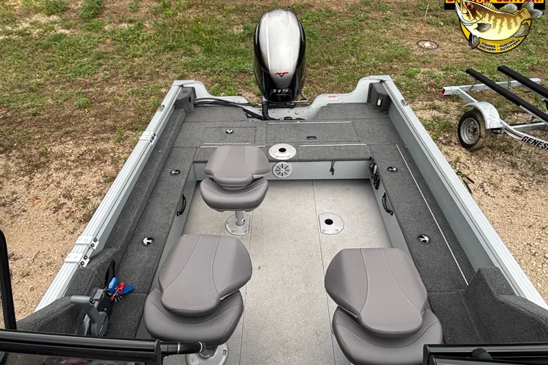 Slide: The Image of 2023 Smoker Craft Excursion 176 DC Pro boat interior with seating and motor, parked on grass. - 9