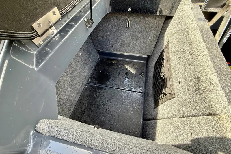 Slide: The Image of Interior storage compartment of 2022 Supra SE 450 boat, featuring carpeted surfaces and netted pocket. - 31