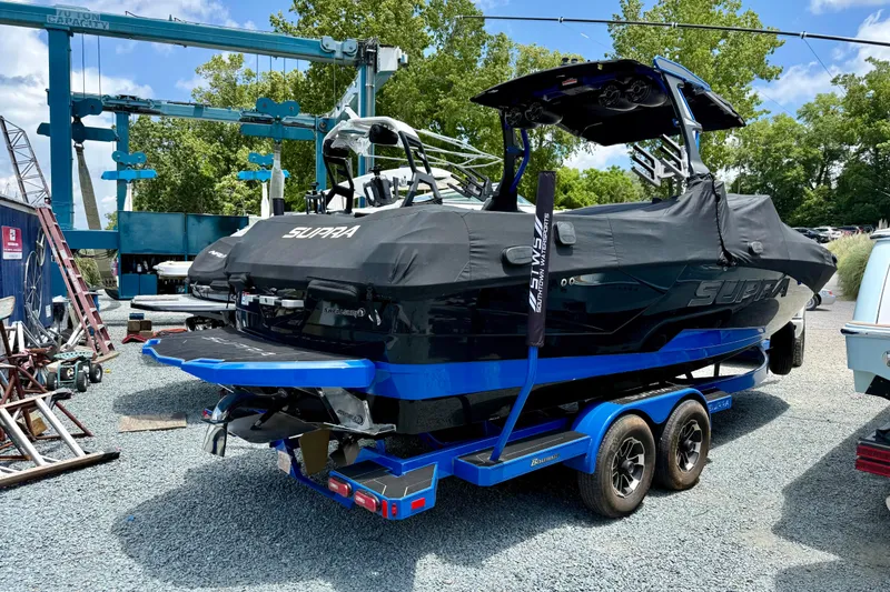Slide: The Image of 2022 Supra SE 450 boat on trailer, covered, in a marina setting. - 9