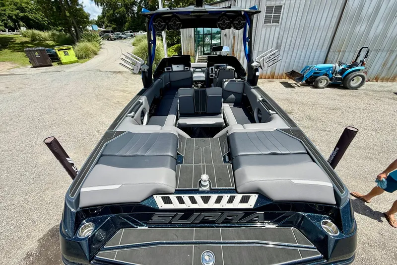 Slide: The Image of 2022 Supra SE 450 boat with sleek seating and modern design, parked outdoors. - 10