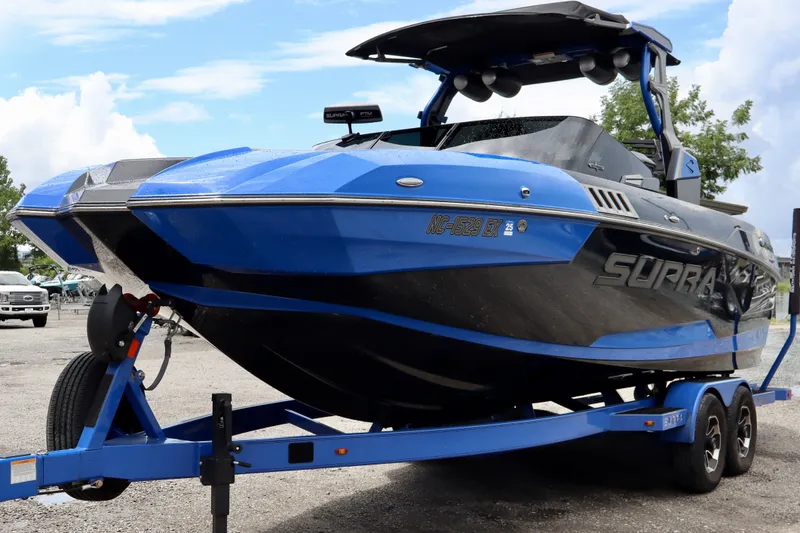 The Image of 2022 Supra SE 450 boat in blue on a trailer, parked outdoors. - 0