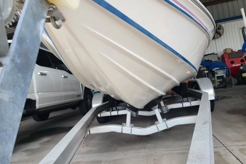 Slide: The Image of 1994 Checkmate Pulsare 2100 boat on trailer in garage setting. - 30