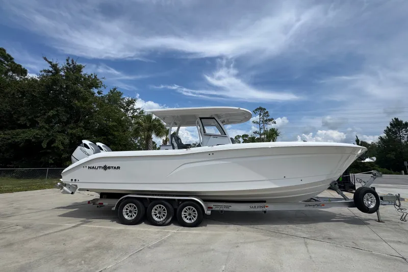 Slide: The Image of 2026 NauticStar 332 Offshore boat on trailer, parked outdoors under a cloudy sky. - 11