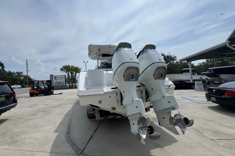 Slide: The Image of 2026 NauticStar 332 Offshore boat with dual outboard engines in a marina parking lot. - 17
