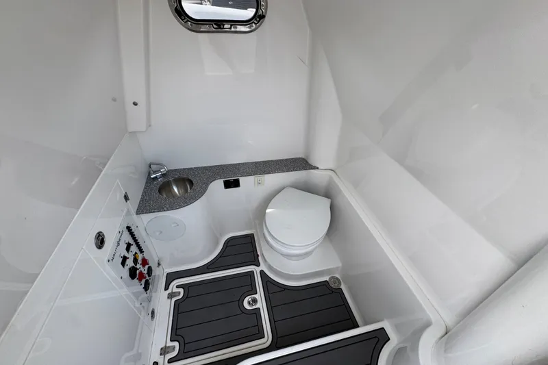 Slide: The Image of 2026 NauticStar 332 Offshore boat bathroom with sink, toilet, and control panel. - 30
