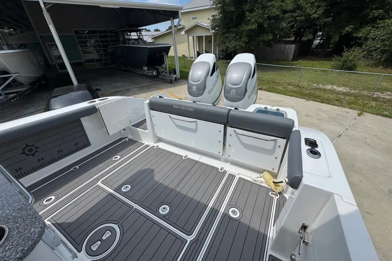 Slide: The Image of 2026 NauticStar 332 Offshore boat with dual Suzuki engines, docked outdoors. - 45