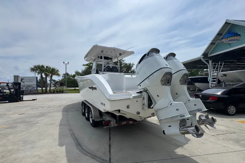 Slide: The Image of 2026 NauticStar 332 Offshore boat with dual engines on a trailer in a marina setting. - 18