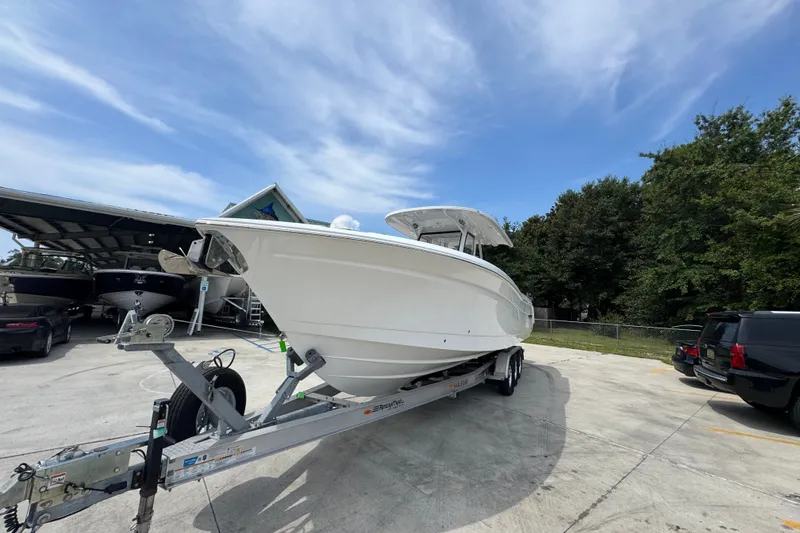 Slide: The Image of 2026 NauticStar 332 Offshore boat on trailer, parked outdoors under a clear sky. - 5