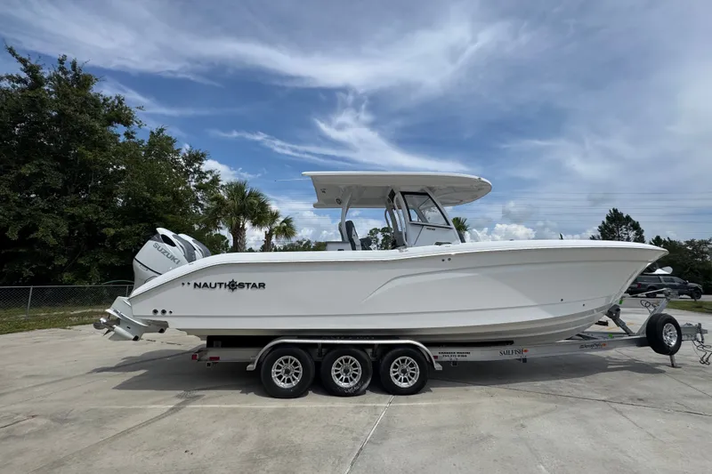 Slide: The Image of 2026 NauticStar 332 Offshore boat on trailer, parked outdoors under a cloudy sky. - 12
